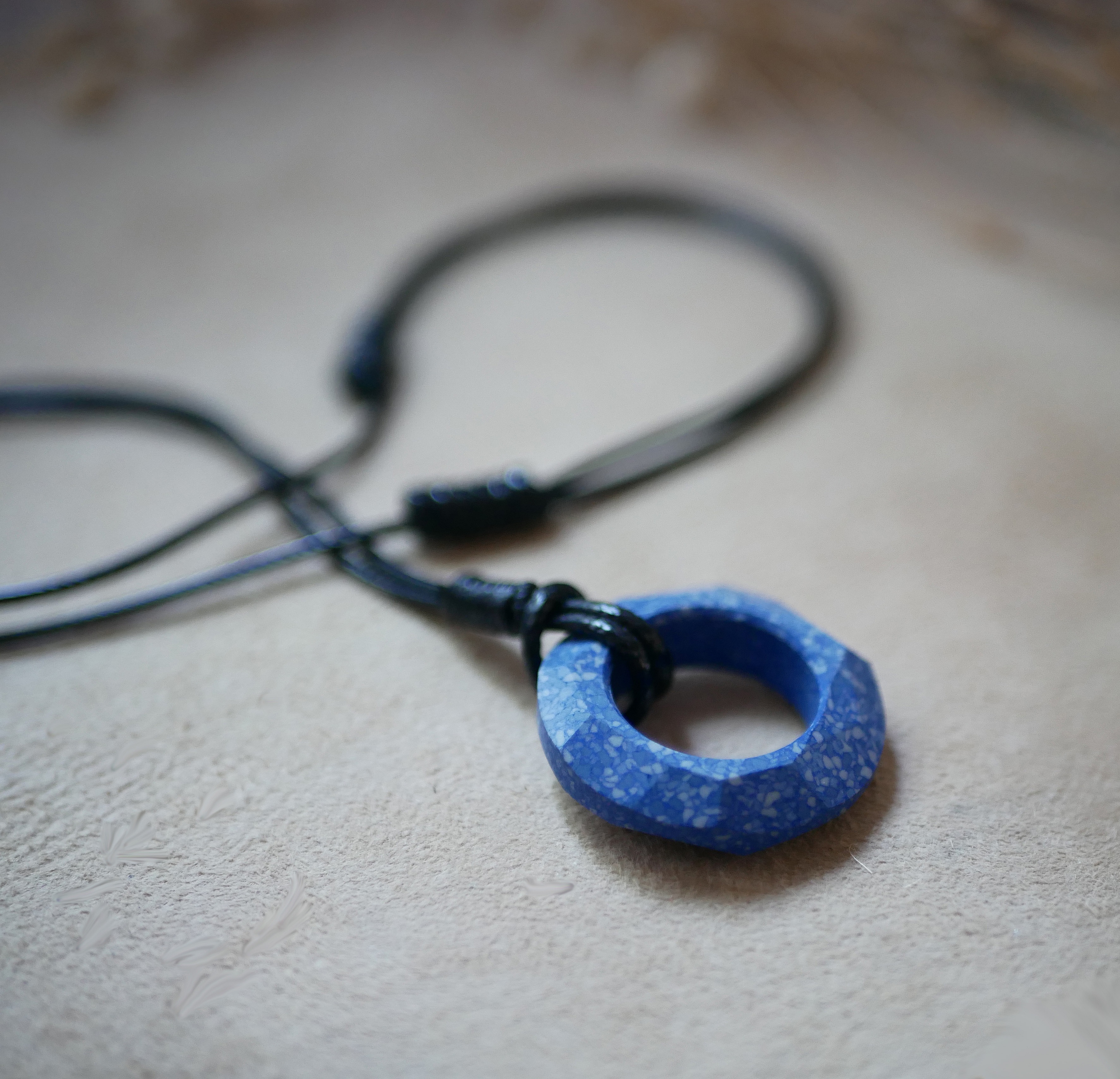 Collier anneau en c&eacute;ramique bleue sur cordon cuir noir ajustable