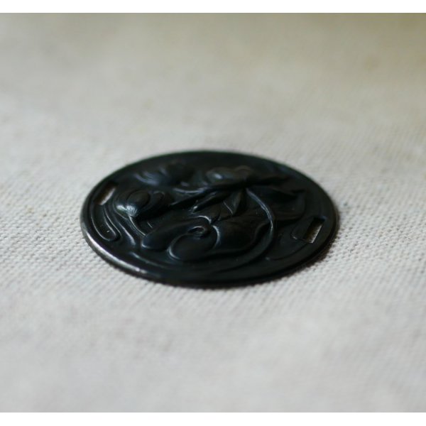 Vandliljemedaljon i sort metalrelief med sideb&aring;nd 