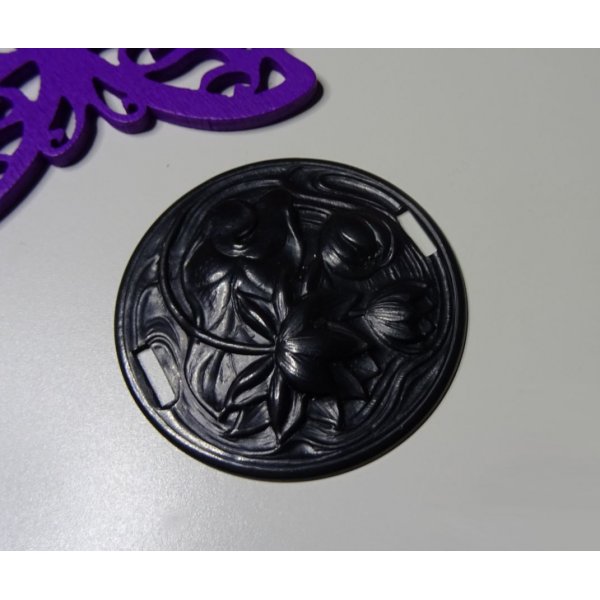 Vandliljemedaljon i sort metalrelief med sideb&aring;nd 